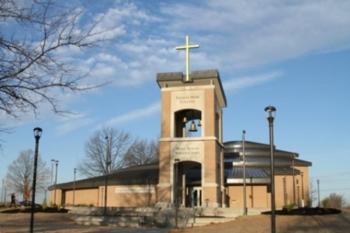 church building with a tall cross and 'Thomas More' sign