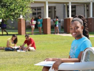 student smiling on campus with others studying in background