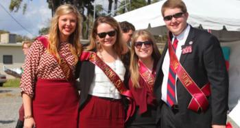 four people smiling with sashes at an outdoor event