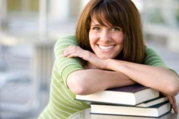 smiling woman leaning on a stack of books