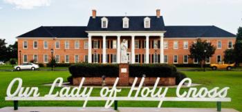 statue in front of building with 'Our Lady of Holy Cross' text