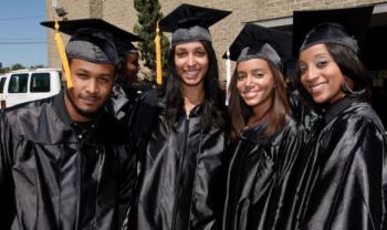 four graduates smiling in cap and gown