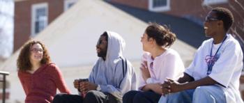 four students sitting and chatting on a sunny day