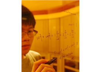 person writing mathematical equations on a glass surface