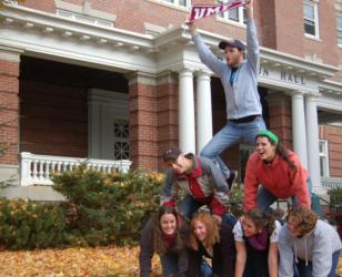 students forming a human pyramid in front of a building