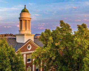 historic building with a cupola on campus at dusk