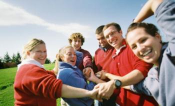 group of people joining hands in a circle outdoors