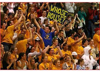 crowd cheering at a sports event with sign 'whose house?'