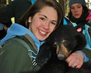 student holding a small bear with onlookers