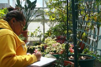 student taking notes in a lush greenhouse