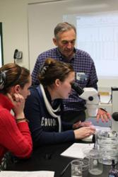 students and professor working with microscope in lab