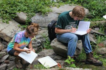 students studying on rocks in an outdoor setting