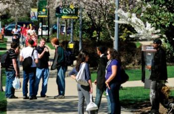 students walking and chatting on campus, 'csm' sign visible