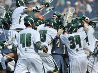 lacrosse team in green and white uniforms celebrating