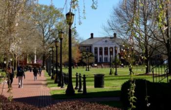 students walking on a campus pathway with trees and a building in the background