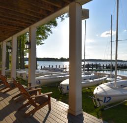 sailboats docked by a lake viewed from a shaded porch with chairs