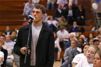 young man speaking at a podium in a gym