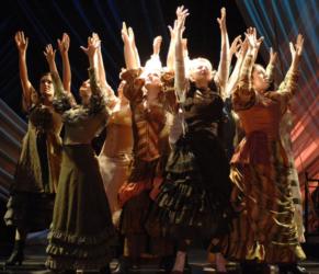 group of dancers performing on stage with arms raised