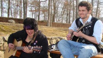 two people playing guitars outdoors on a sunny day