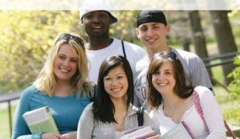 group of smiling students holding books outdoors