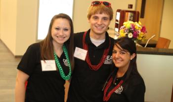 three smiling students with lanyards and name tags