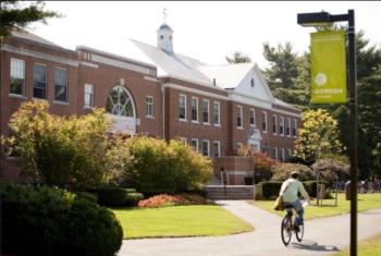 person biking past a brick building with a green banner