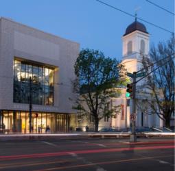 modern building next to a classic white spire at dusk