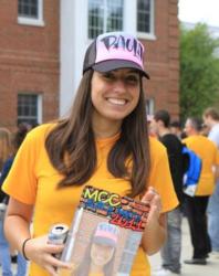 smiling person holding a magazine with 'mcc' cap