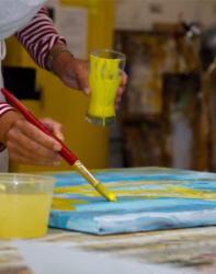 person painting on canvas with yellow paint