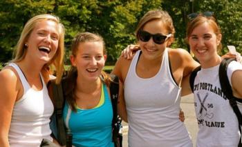 four smiling students with backpacks outdoors