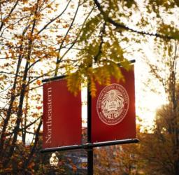 northeastern university seal on a signpost with autumn foliage