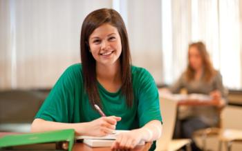 smiling student taking notes in a classroom