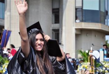 graduate waving in cap and gown at commencement