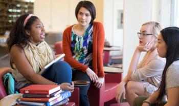 students in a discussion with books on table
