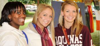 three smiling students with 'aquinas' on clothing