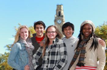 five students smiling with clock tower in background