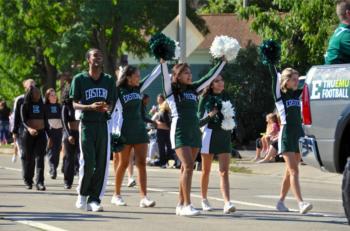 cheerleaders and mascot in green and white at a parade