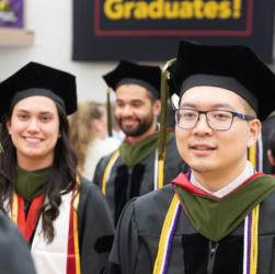 graduates wearing caps and gowns with 'Congratulations Graduates!' banner