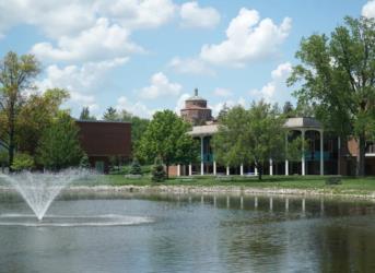 lake with fountain in front of university buildings