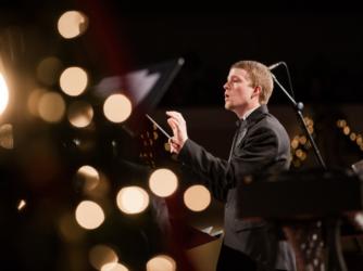 conductor leading an orchestra with bokeh lights