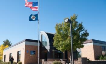 us flag and school flag flying over college campus building