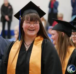 smiling graduate in cap and gown with honor cords