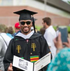 graduate in cap and gown holding diploma