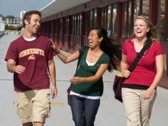 three students smiling and walking outside