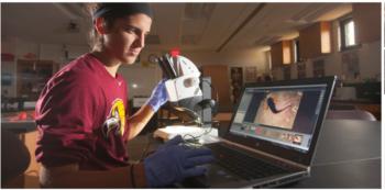 student in lab with glove and electronic device