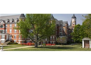 historic building with a clock tower behind trees