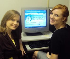 two people posing by a computer with 'southeastern baptist col' on screen