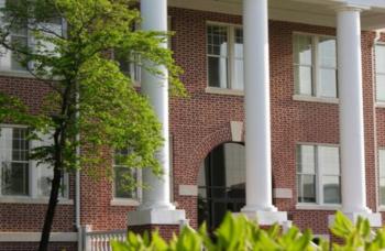 brick building with white columns and greenery