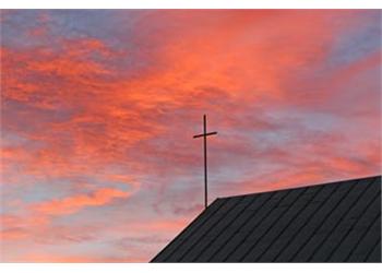 sunset sky with clouds behind a cross on a roof