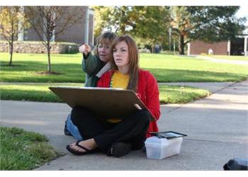 student studying on grass with child pointing